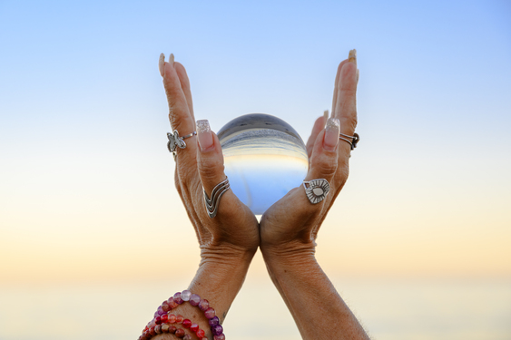 Diferencias entre Registros Akáshicos y Tarot, manos sosteniendo esfera de cristal frente al mar.